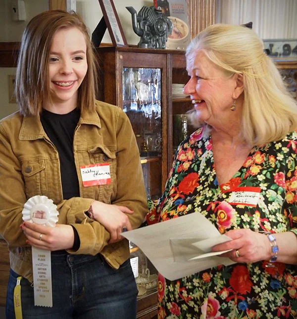 A woman giving an award to a teenage